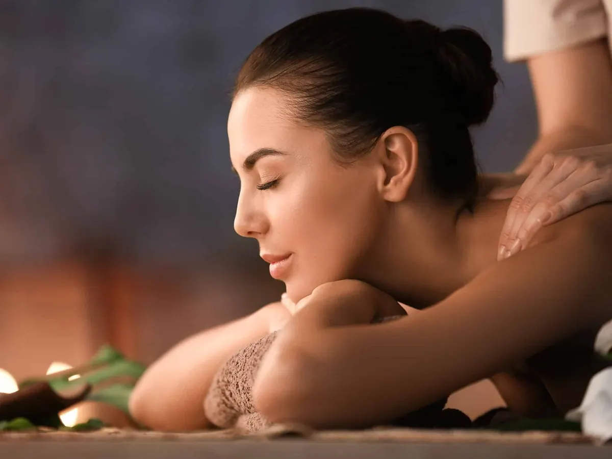 Cliente rilassata durante un massaggio svedese con candele e oli